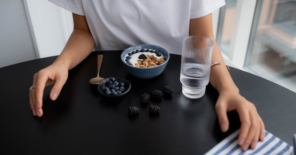 A healthy breakfast of granola with blueberries and blackberries, served with water.