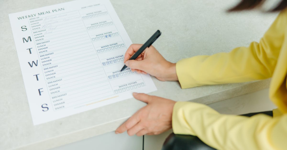 Woman writing on a weekly meal plan checklist indoors, focusing on diet organization.