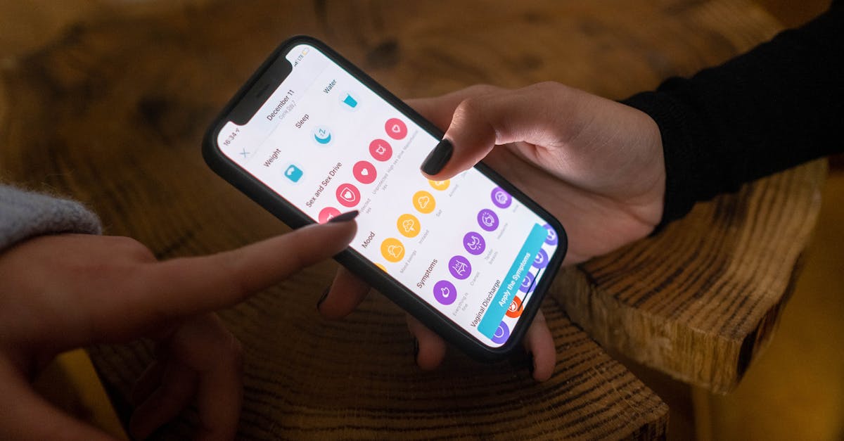 Close-up of hands using a fertility tracking app on a smartphone indoors.