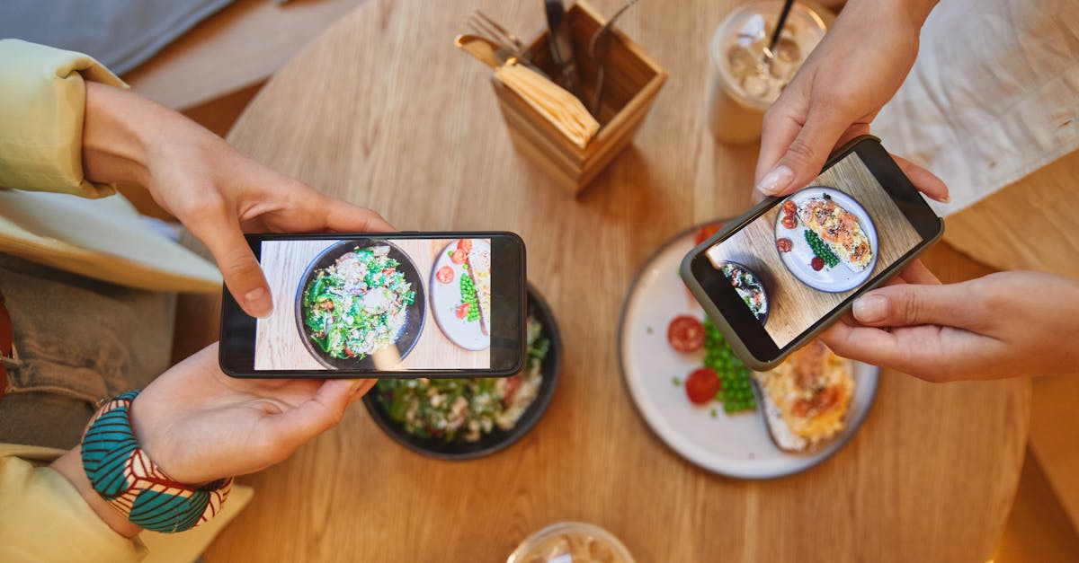 Two people taking photos of brunch dishes with smartphones in a cozy cafe setting.
