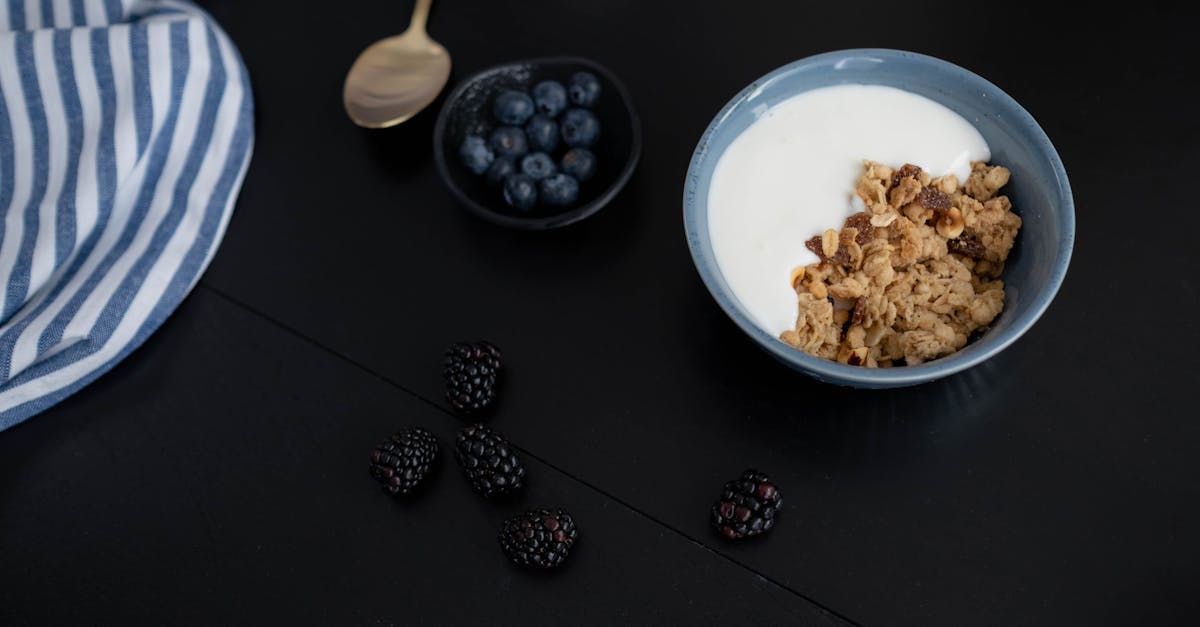 A healthy breakfast bowl with granola, yogurt, blackberries, and blueberries.