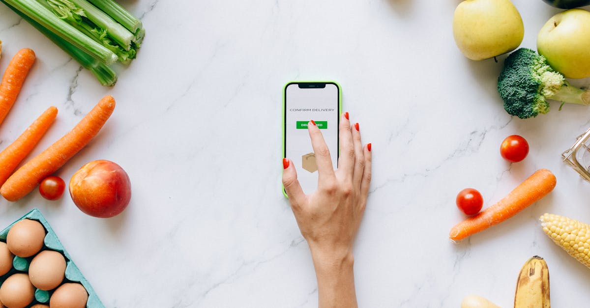 Flat lay of fresh vegetables and fruit with a smartphone showing grocery delivery confirmation.